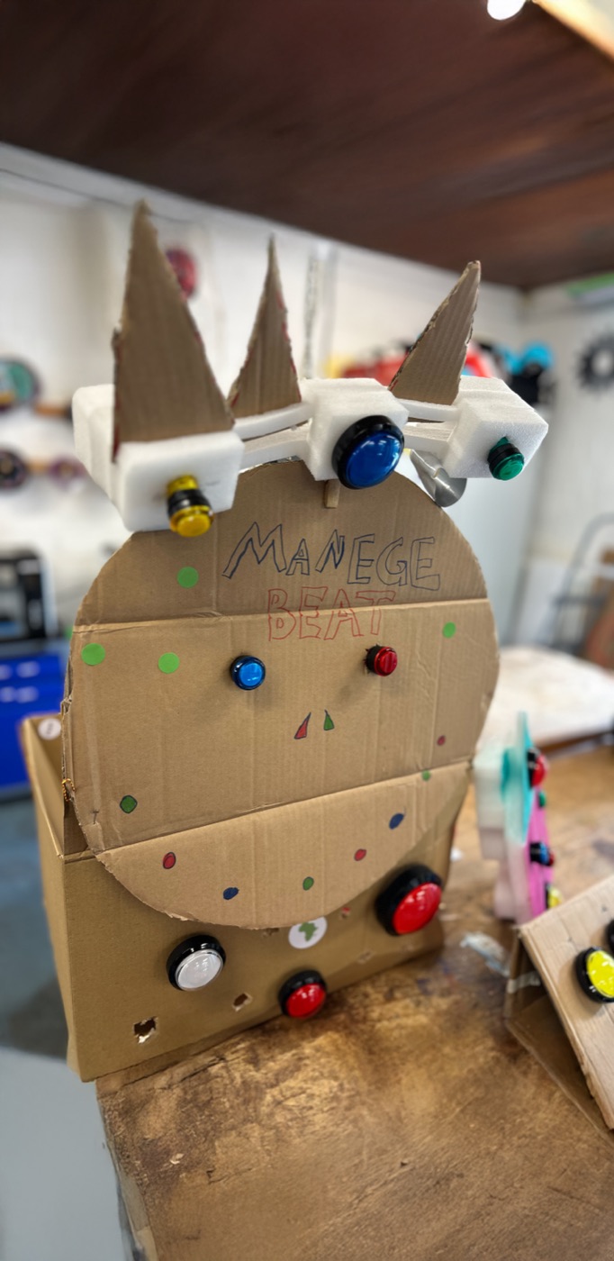 Beatmaschine aus Pappe mit Arcade-Knöpfen, beschriftet mit MANEGE BEAT